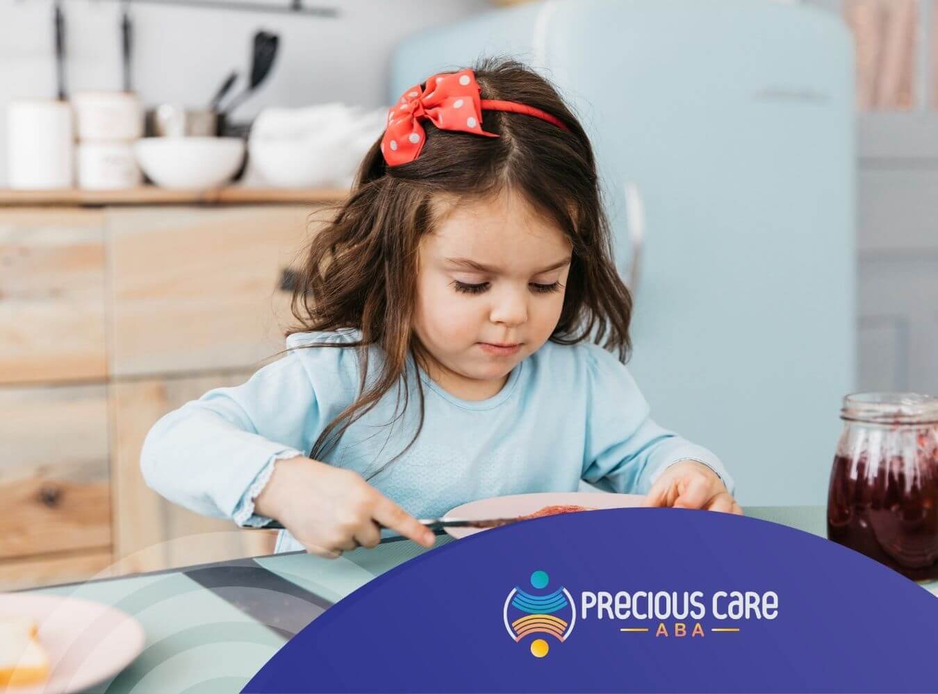 A young girl with autism is spreading jam on a slice of bread at the breakfast table.