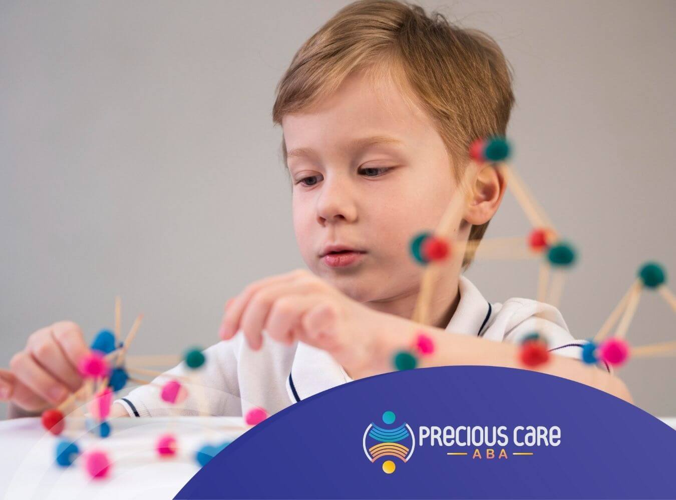 A child with autism is constructing a structure with pom-poms and toothpicks during ABA therapy.
