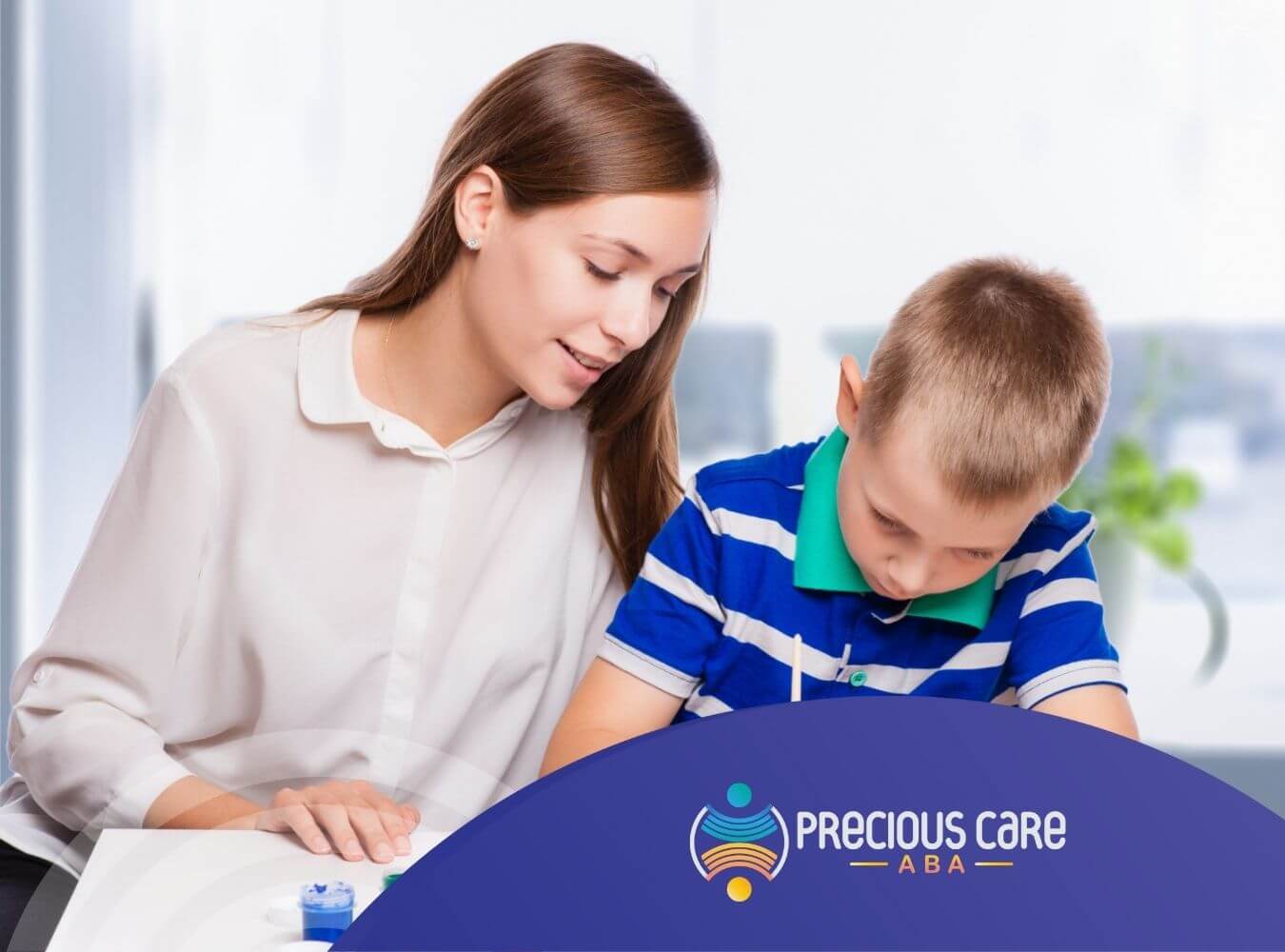 An ABA therapist and a child are painting together at a table in ABA therapy.
