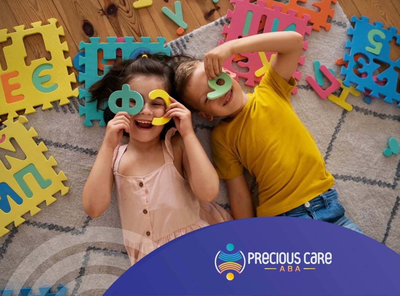 Two children lie on a textured rug surrounded by colorful foam letters and numbers.