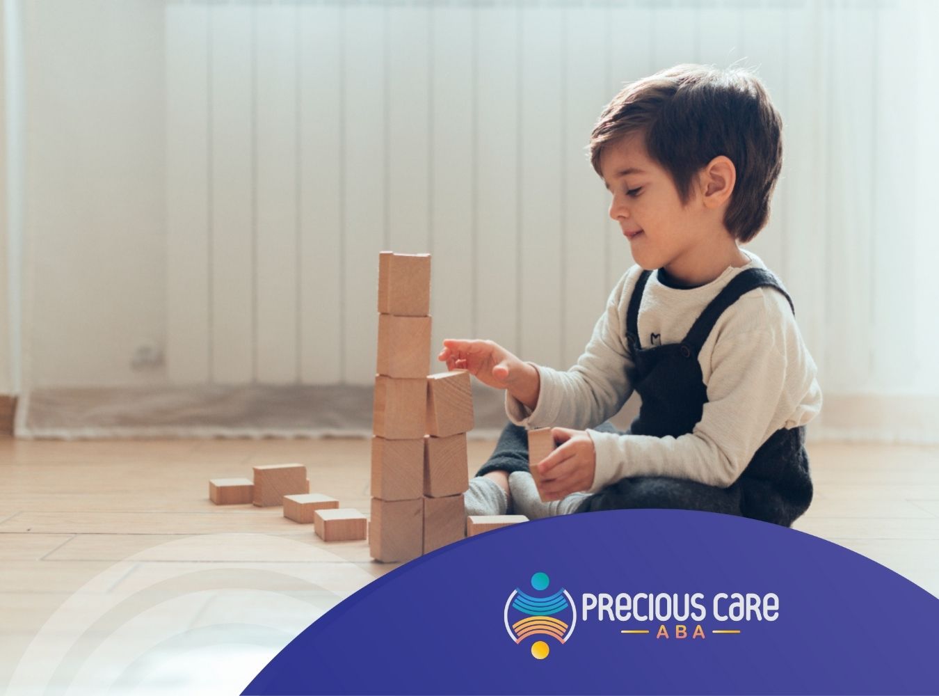Autistic boy playing with wooden blocks, building a tall tower on the floor.