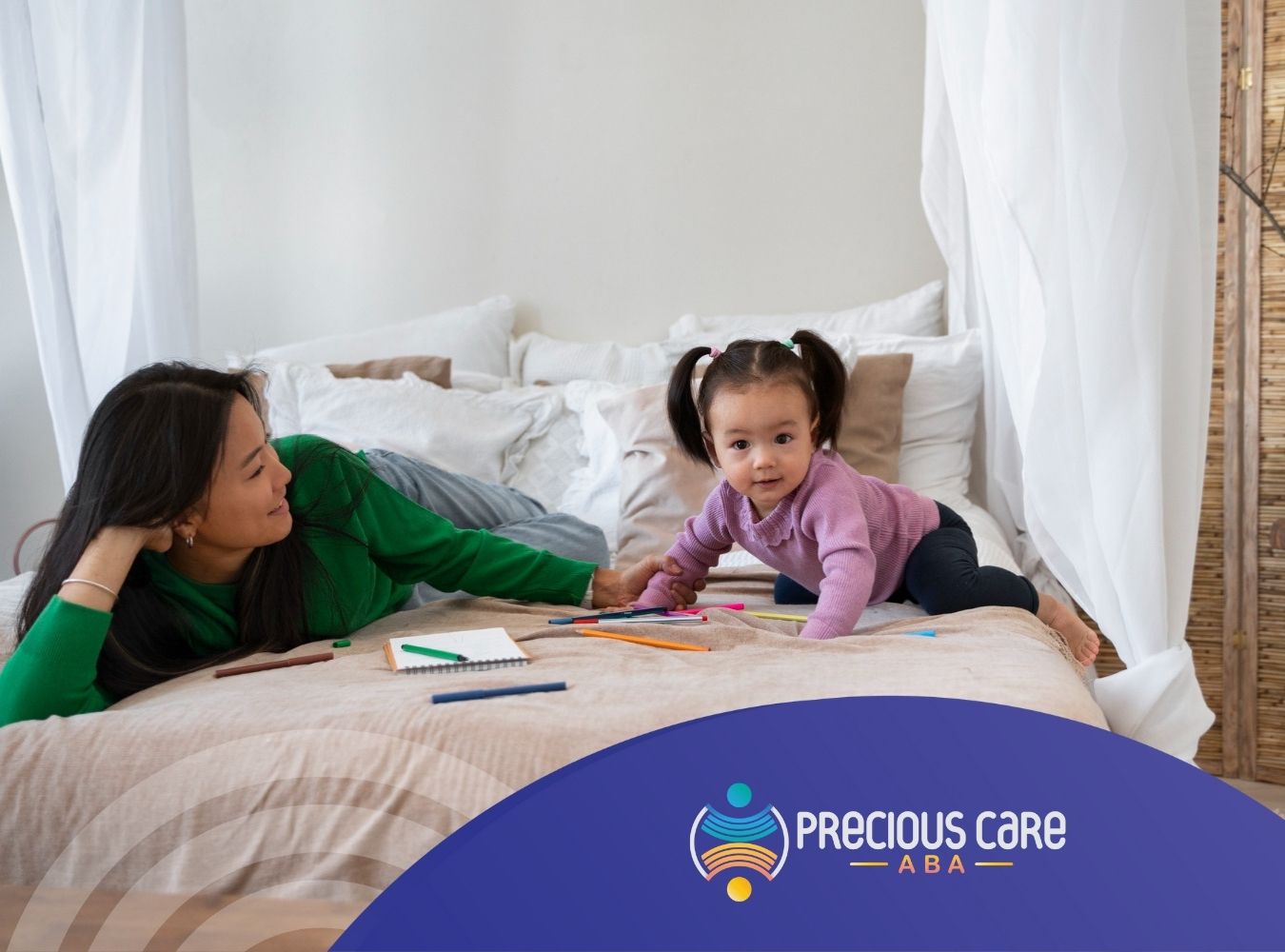 Mother and autistic daughter on a bed playing with colorful markers and paper.