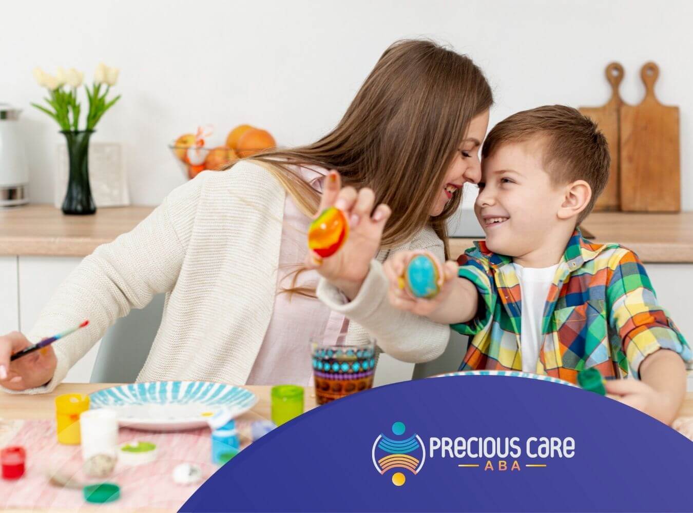 A mother and autistic son smile at each other while painting eggs together after in-home ABA session.