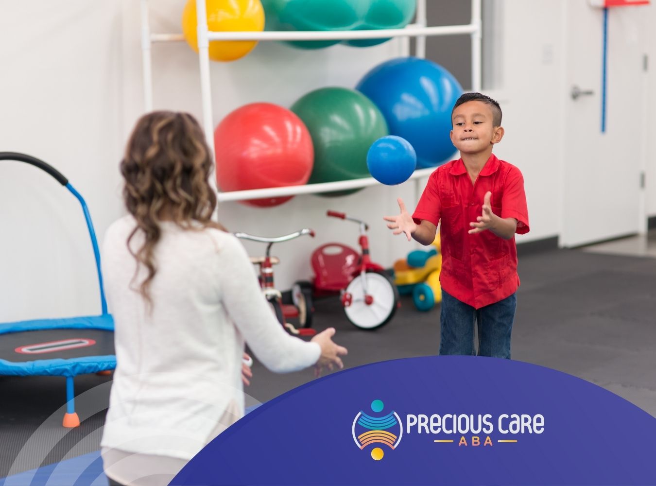 A little boy throwing a ball to his ABA therapist.