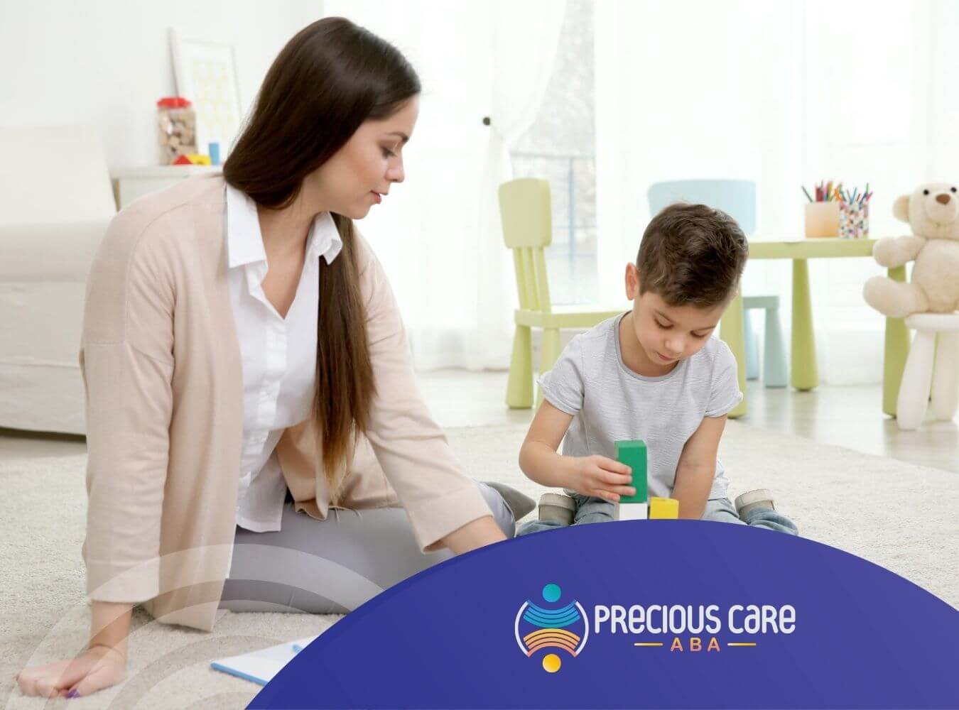 ABA therapist playing with boy and building blocks during ABA therapy.