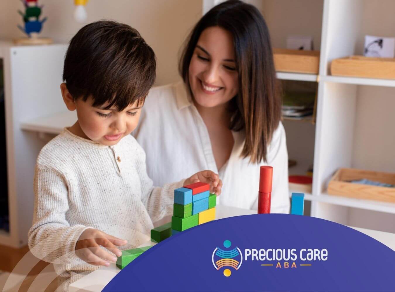 ABA therapist and autistic boy building colorful block towers together at a table in ABA therapy.