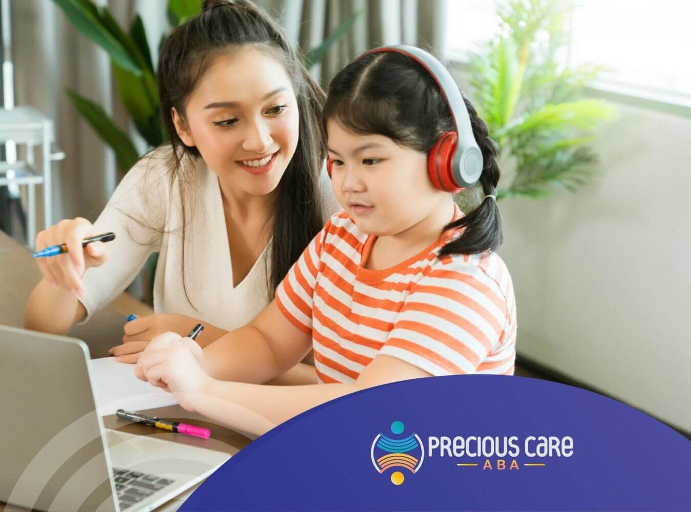 ABA therapist and girl with headphones studying a second language using a laptop and paper.