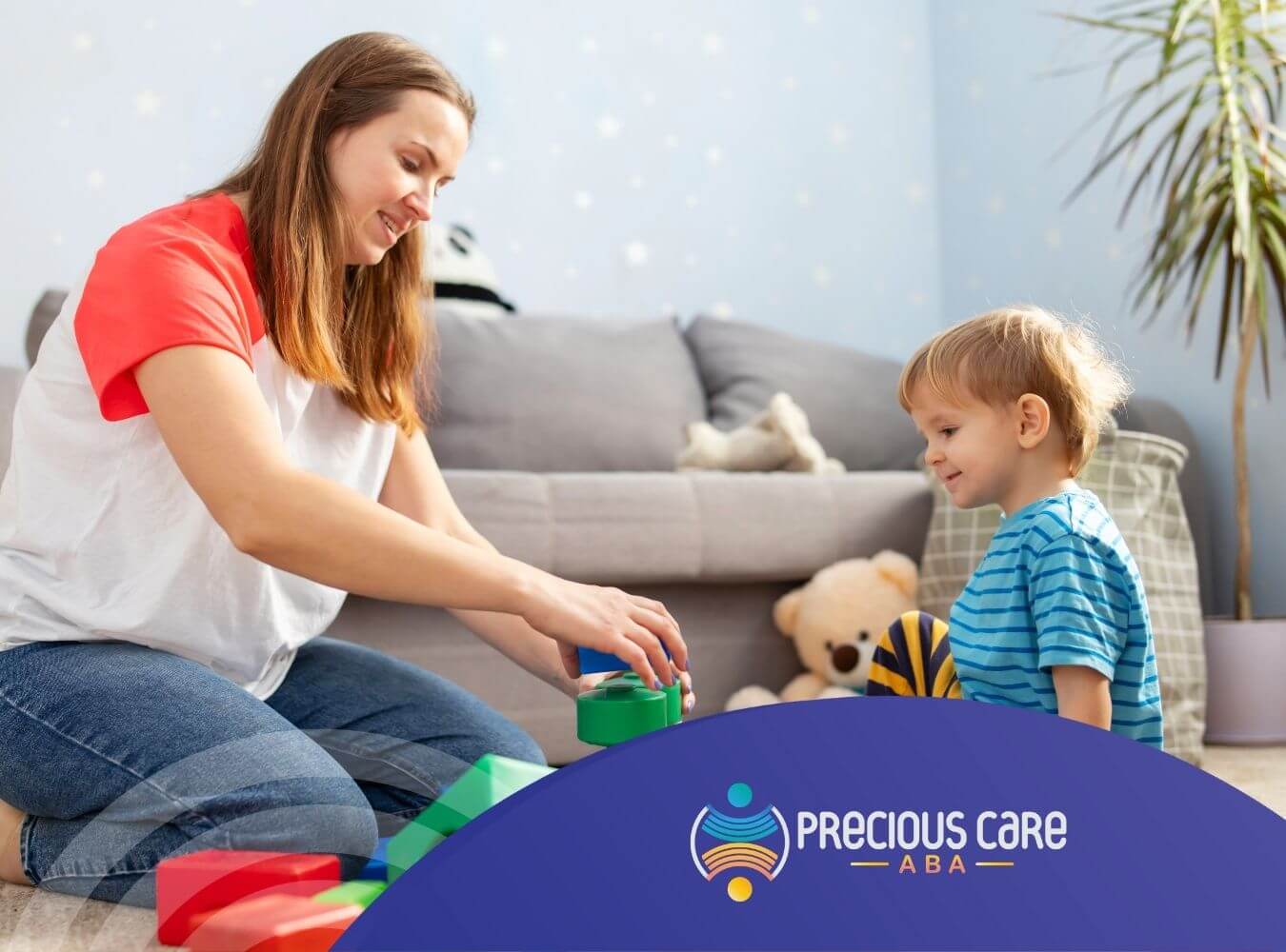 ABA therapist and toddler sit on the floor surrounded by colorful toys and blocks in ABA therapy.