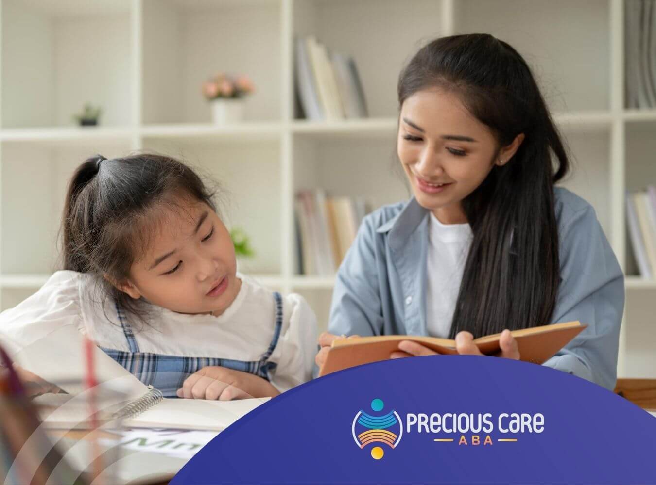 An ABA therapist and a young girl with sitting working together with books and papers in ABA therapy.