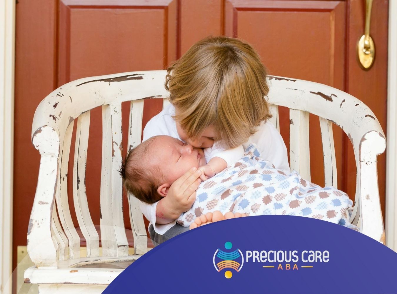Young autistic child kissing newborn baby sibling on a white wooden bench during ABA therapy outdoors in NJ.