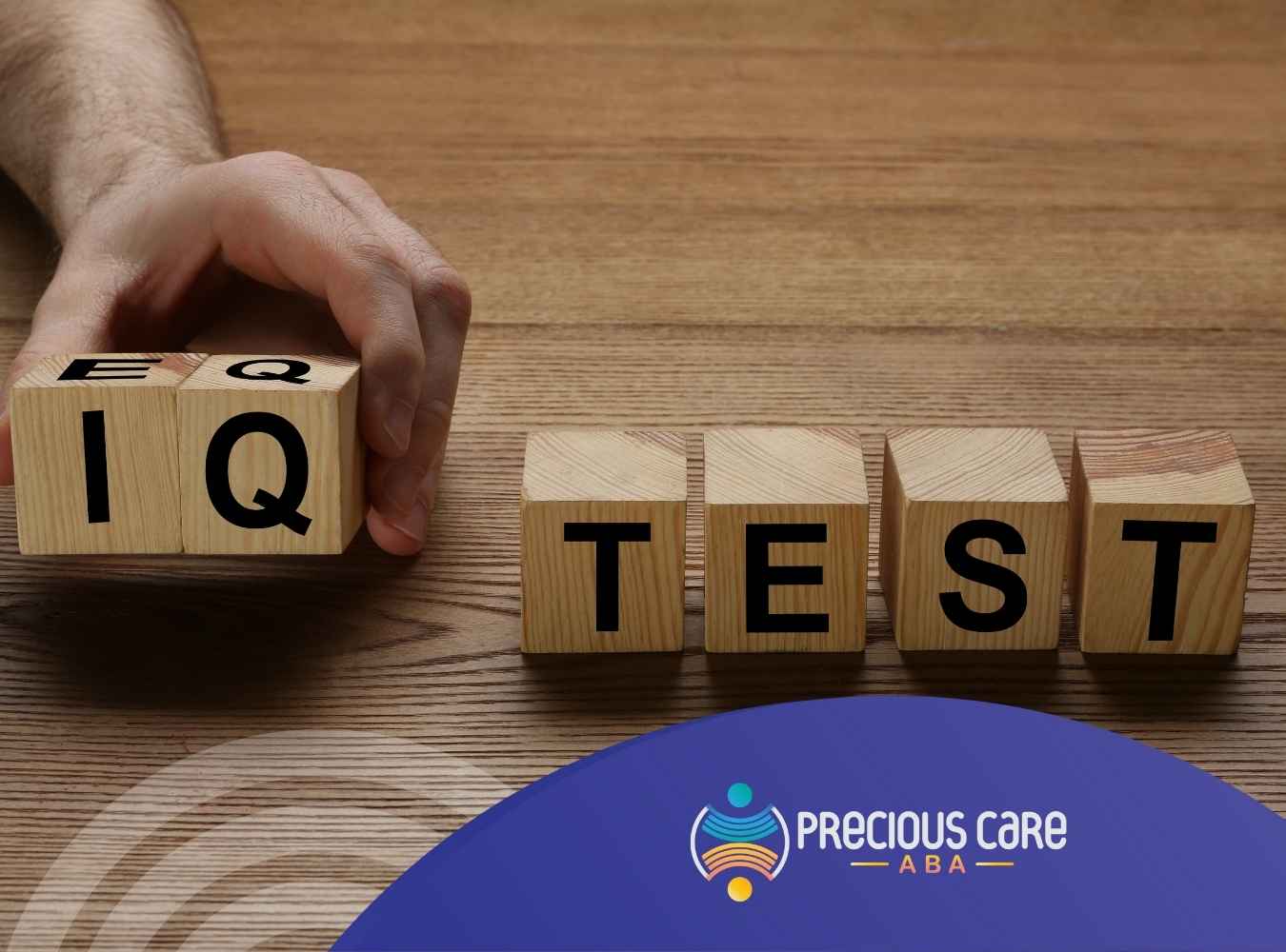 A hand holds wooden blocks with letters “EQ” in front and “IQ” facing out on a table. Next to it are blocks spelling “TEST.”