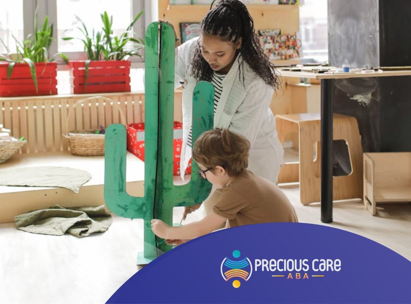 A BCBA helping an autistic child paint cardboard cactus during a school-based ABA therapy in Colorado.