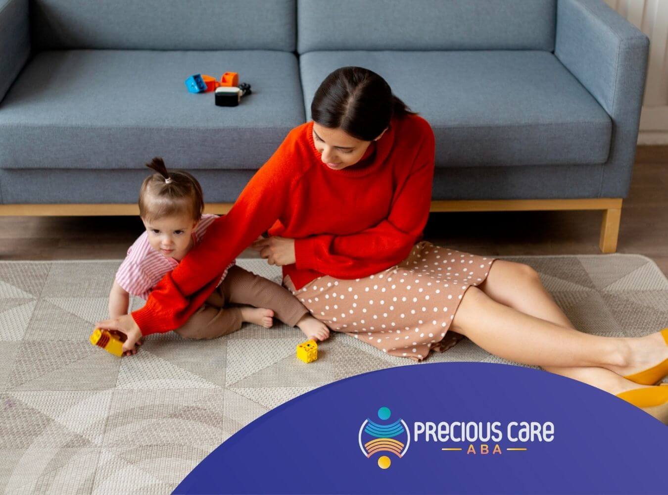 BCBA sitting on floor playing with baby and toy blocks in ABA therapy.