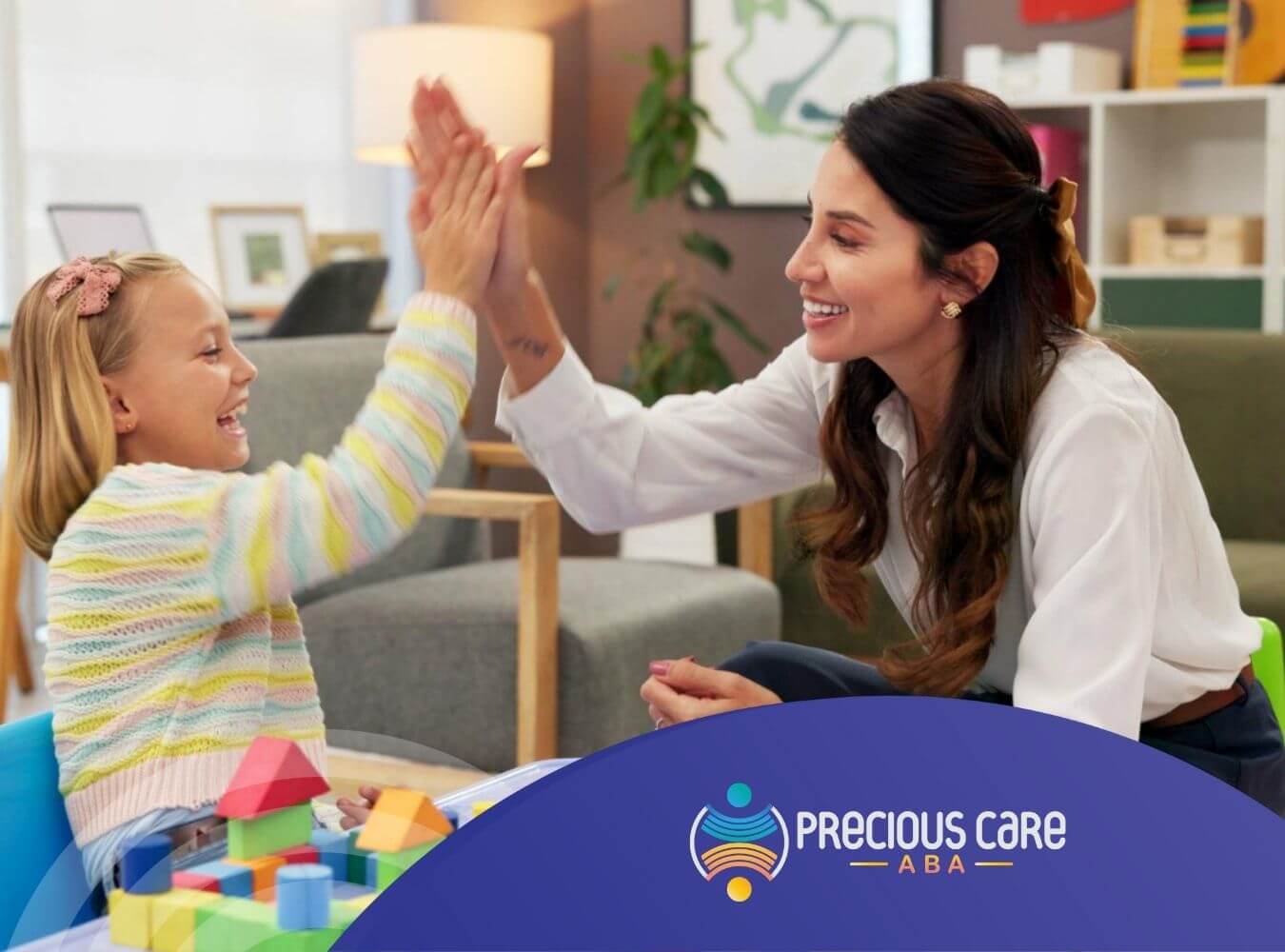 ABA therapist high-fiving child with autism while playing with blocks in ABA therapy.