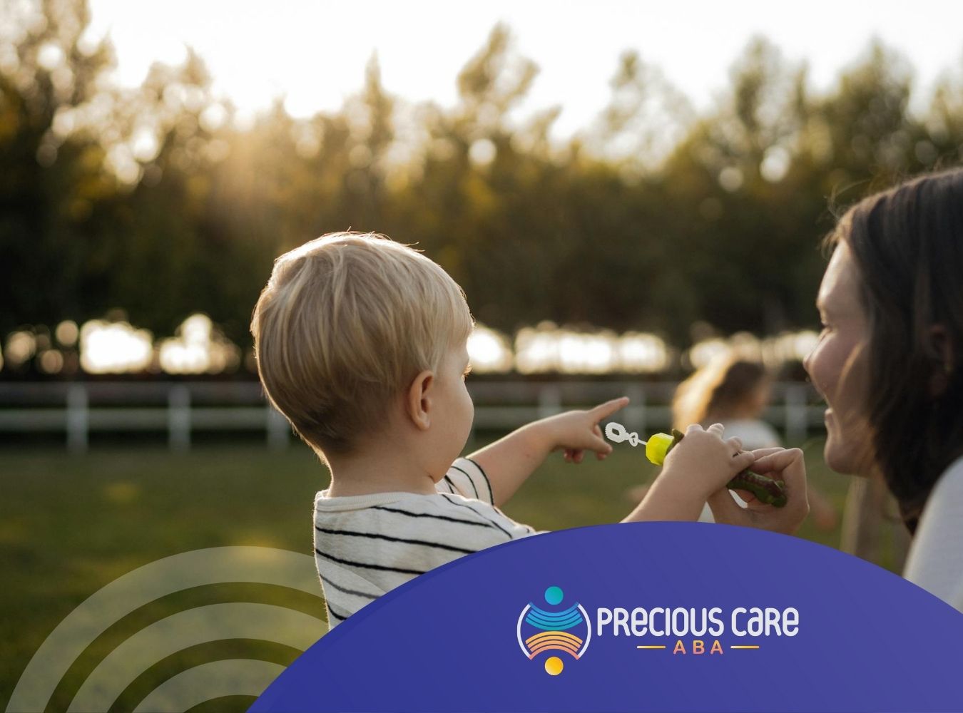 An autistic child pointing outdoors while holding bubble wand playing with his mom during ABA therapy in CO.