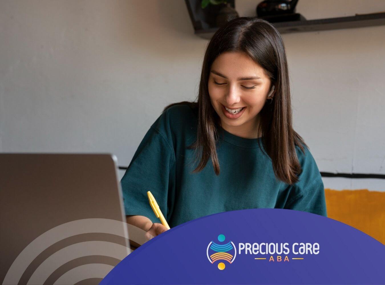 Young woman with autism smiling while writing notes at desk with laptop.