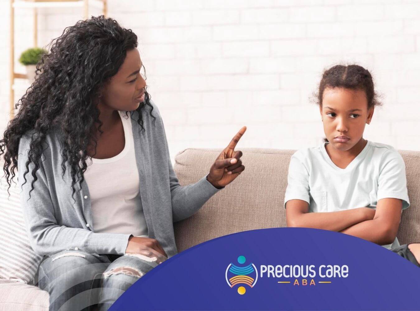 Parent talking to child with autism who looks upset on the couch.