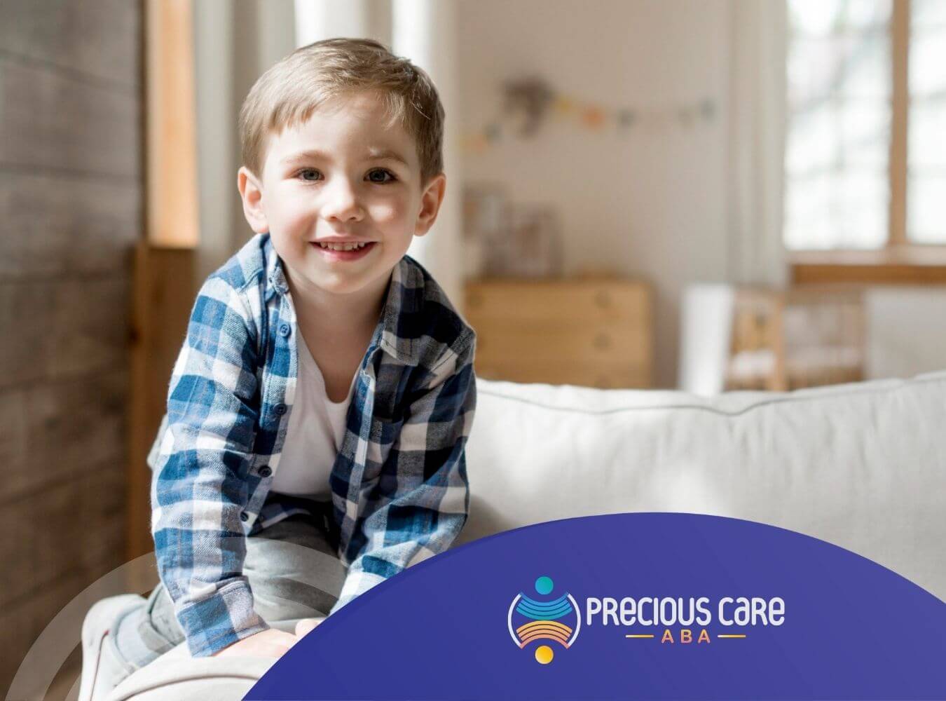 Happy boy with autism in plaid shirt sitting on the back of a couch.