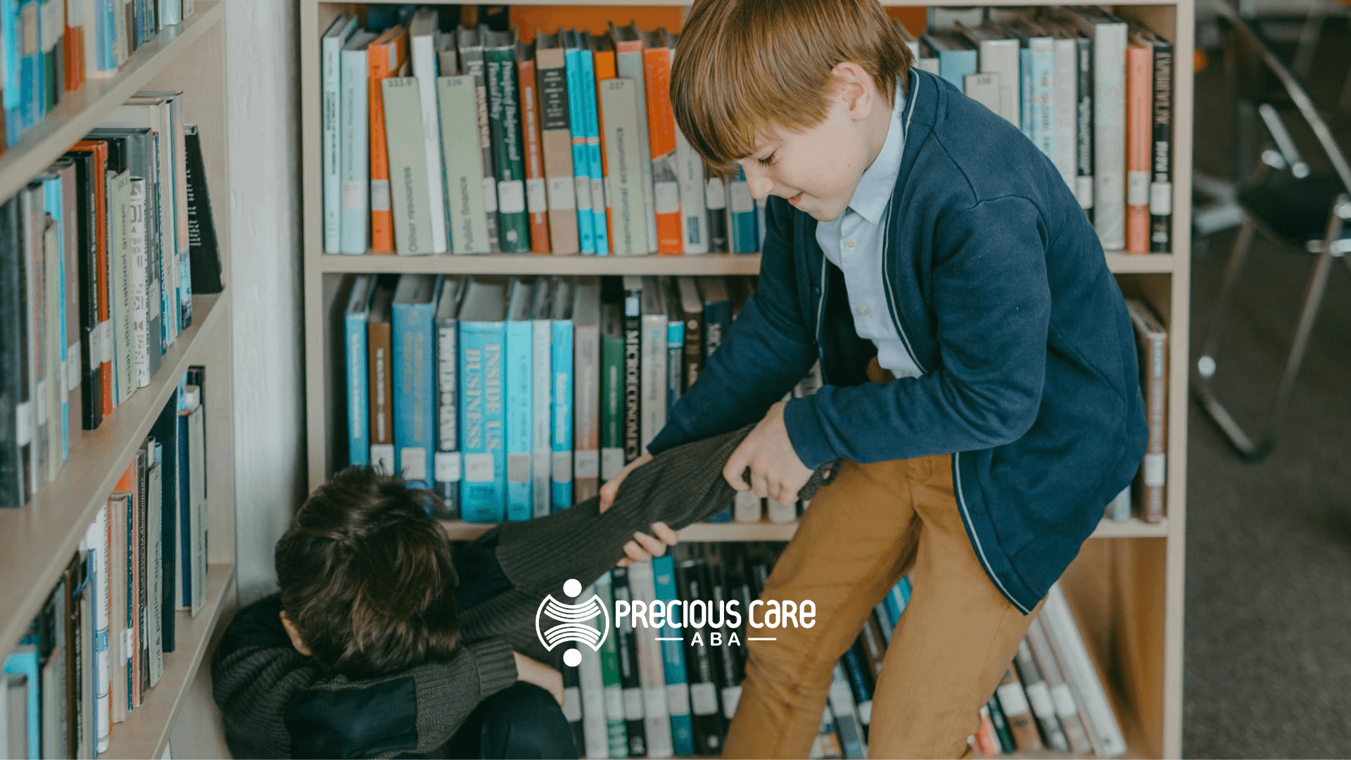 Autistic boy helping another boy up from the floor in a school library and or trying to have a fight