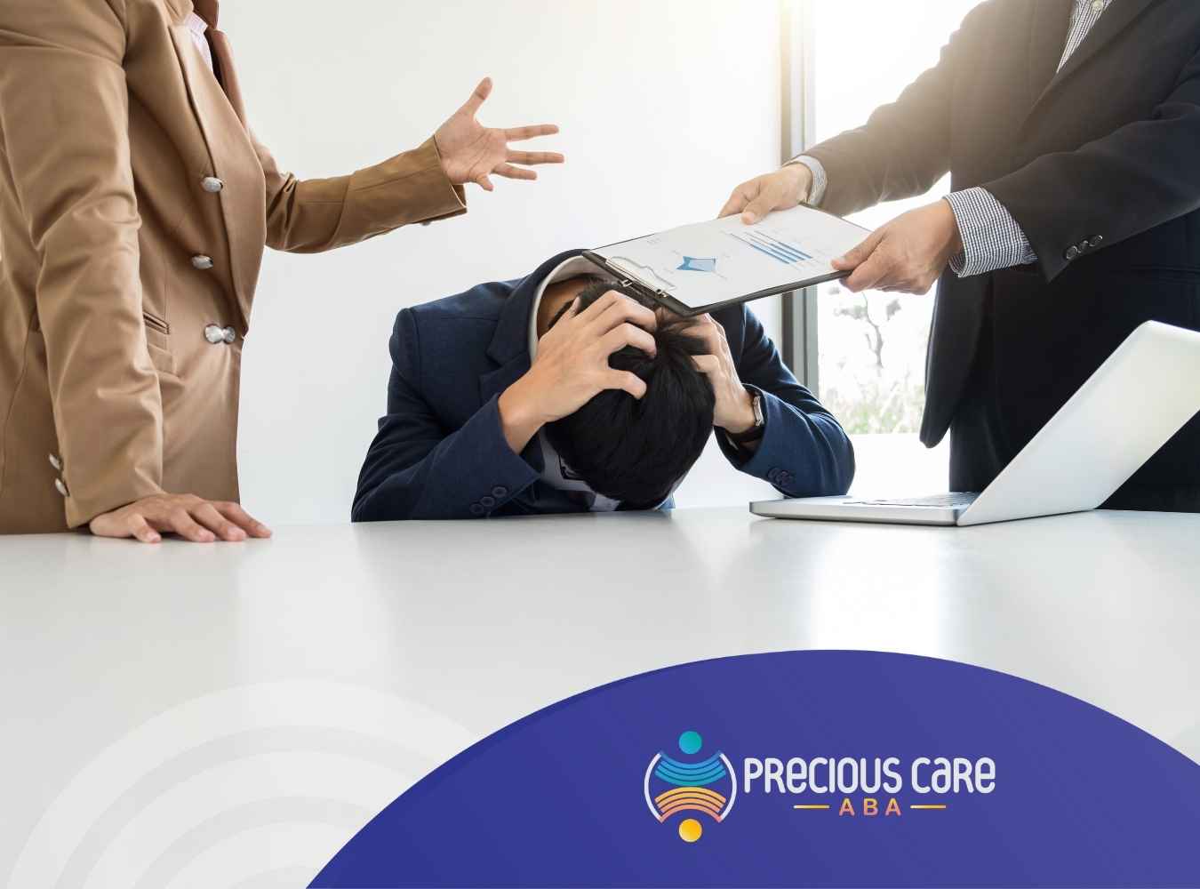 A stressed man in a suit covers his head with his hands at a table as two colleagues show documents, expressing tension and workplace pressure.