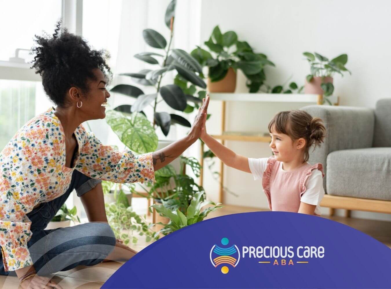 Female BCBA and child with autism high-five while playing indoors during ABA therapy.