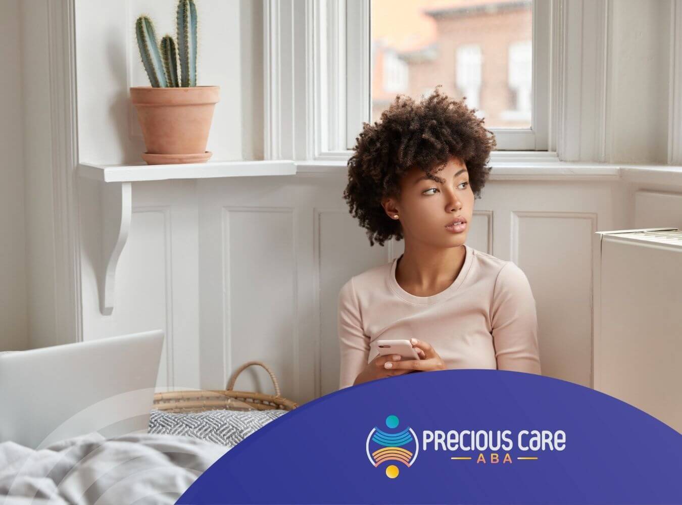 Woman with autism sitting by window holding phone, looking away.