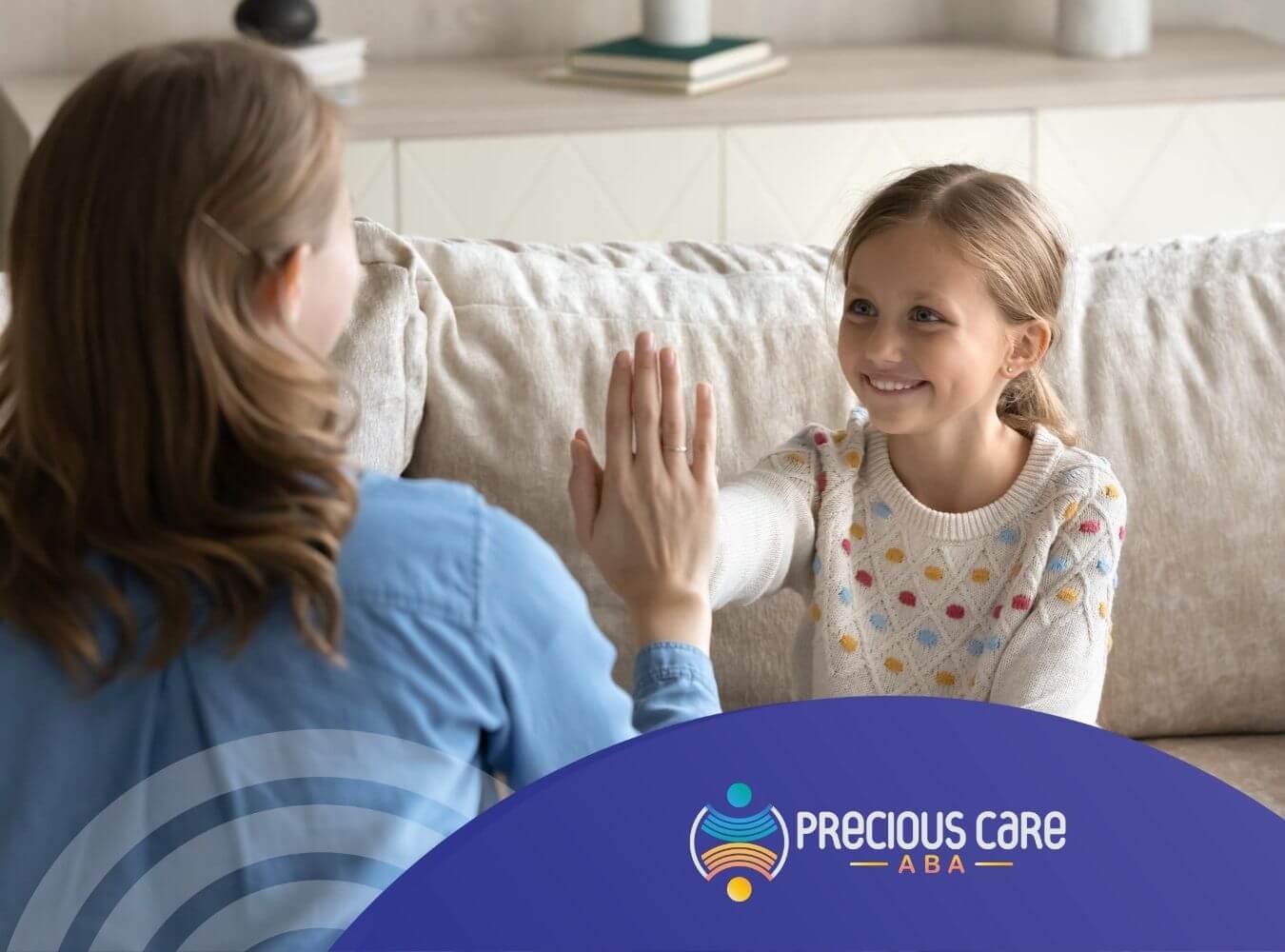 Therapist and young girl with autism on a couch giving each other a high-five during ABA therapy session.