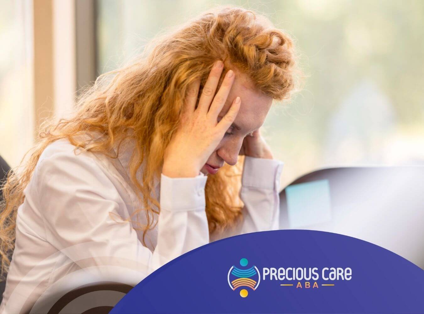 Stressed woman with autism holding head at desk.