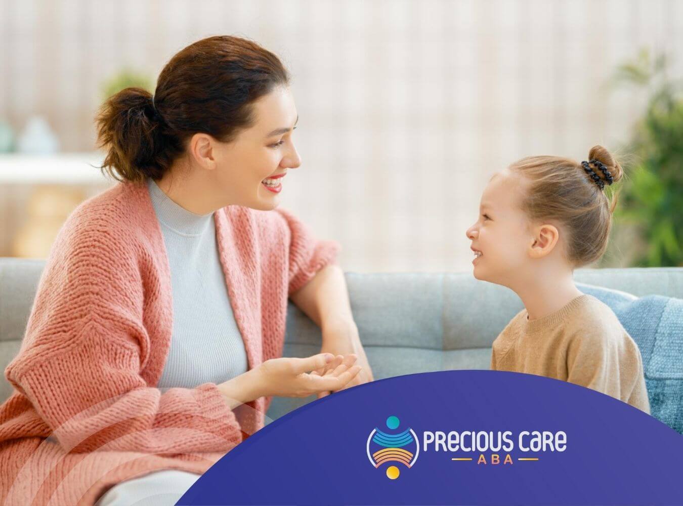 Therapist and young child with autism sitting on a couch, smiling and talking together.